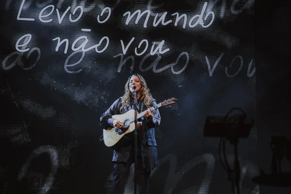 Fotografia colorida mostrando cantora com violão em palco-Metrópoles