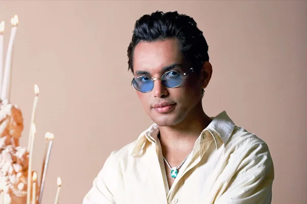 foto colorida de homem negro de oculos com lentes azuis e camisa amarela - metrópoles