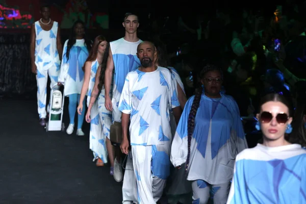 Pacientes com doença rara no desfile de Walério Araújo no SPFW N53. Todos usam roupas brancas com borboletas azuis