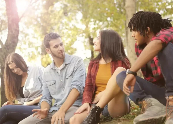 quatro jovens conversando sentados em um banco em um parque