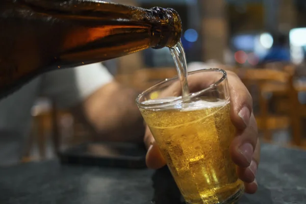 Imagem colorida de garrafa de cerveja enchendo copo - Metrópoles
