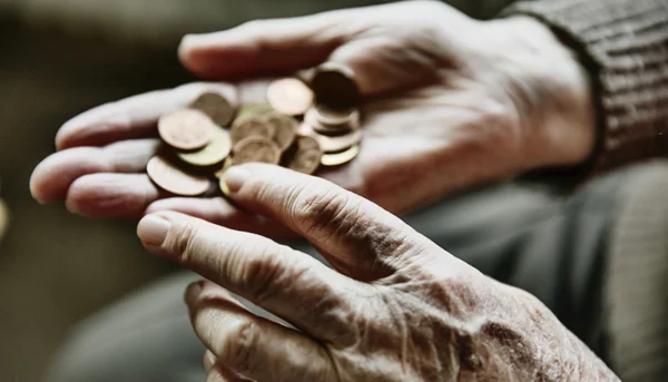 mãos de uma pessoa idosas seguram moedas