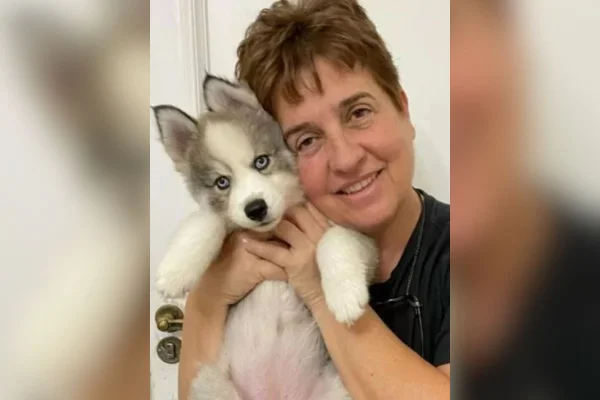 Imagem colorida mostra a engenheira Eliane Toniolo, uma mulher branca, de cabelos curtos avermelhados, segurando um cachorro de pelos brancos e cinzas - Metrópoles