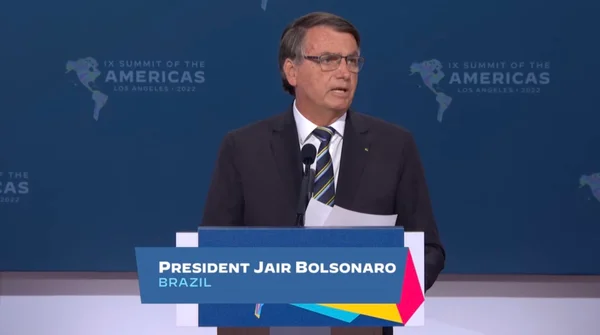 O presidente Bolsonaro discursa em púlpito na Cúpula das Américas. Ele usa óculos e fala num microfone, com papéis em mãos - Metrópoles