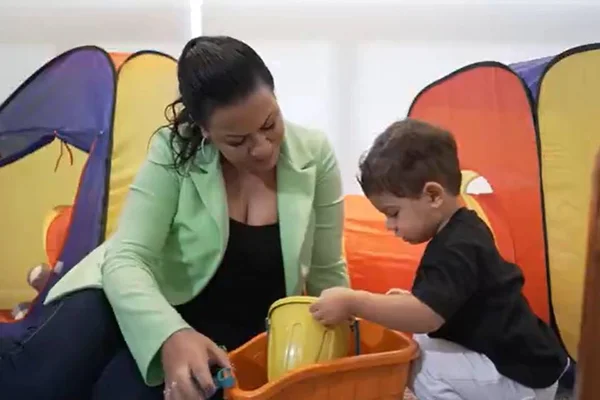 uma mulher de blazer verde ao lado de uma criança de blusa preta