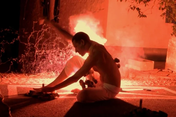 Imagem colorida de um homem com fogo atrás | Filme Presença que explora limite entre o corpo e arte | MEtrópoles