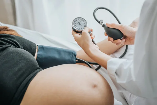 Foto de médica aferindo a pressão de gestante em consultório - Metrópoles - eclâmpsia