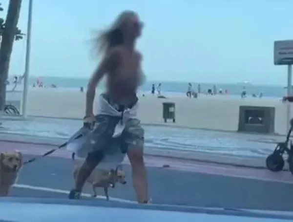 Imagem colorida de uma mulher com os seios a mostra e dois cães em SC - Metrópoles