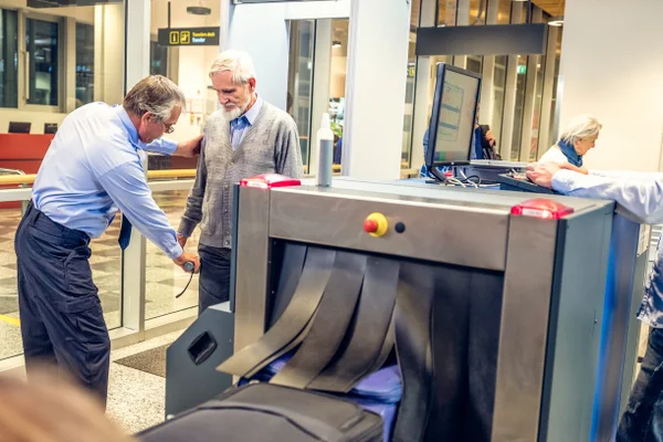 Foto colorida de homem sendo revistado em aeroporto. Imagem ilustrativa - Metrópoles