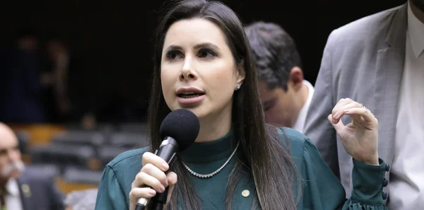 Deputada Carol di Toni usa blusa verde e fala ao microfone