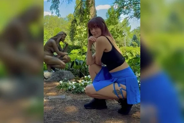 Mulher jovem posando para foto ao lado de um estátua - Metrópoles.