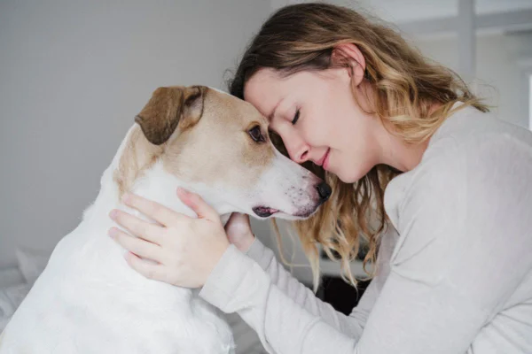 Imagem colorida de mulher acariciando cachorro