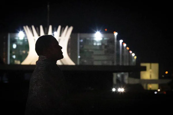 Foto colorida de homem à noite em frente à catedral