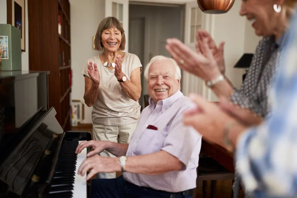 Pessoas mais velhas em torno de um piano, enquanto cantam e tocam - Metrópoles