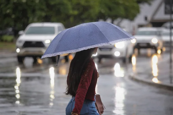 Foto colorida mulher usando guarda-chuva - Metrópoles