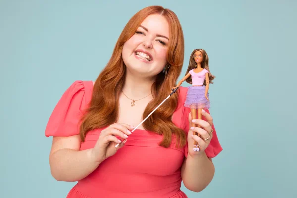 Imagem colorida de uma influenciadora segurando uma Barbie | Metrópoles