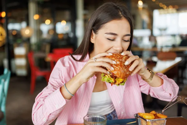 foto colorida de mulher comendo hambúrguer
