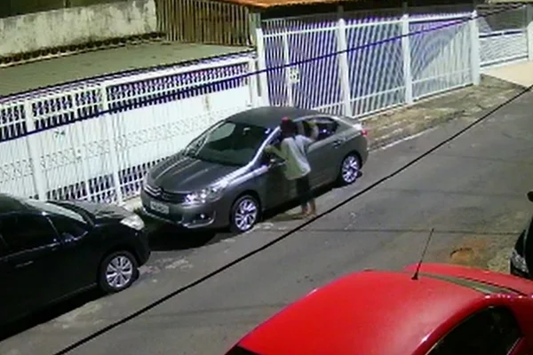 mulher com braço erguido em frente a carro