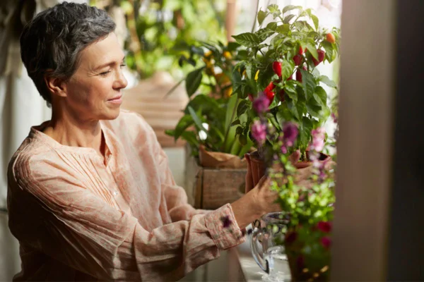Imagem colorida de mulher cultivando plantas em casa