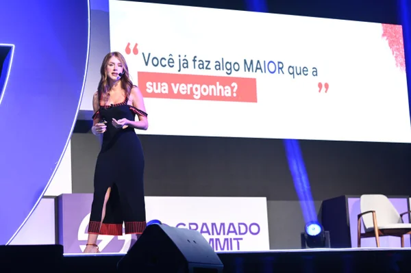 Fotografia colorida mostrando mulher palestrando sobre palco com telão atrás-Metrópoles