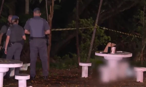 Imagem colorida de policiais em uma praça, à noite