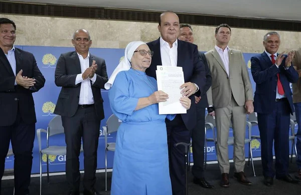 Mulher vestida de freira ao lado de homem careca de terno preto