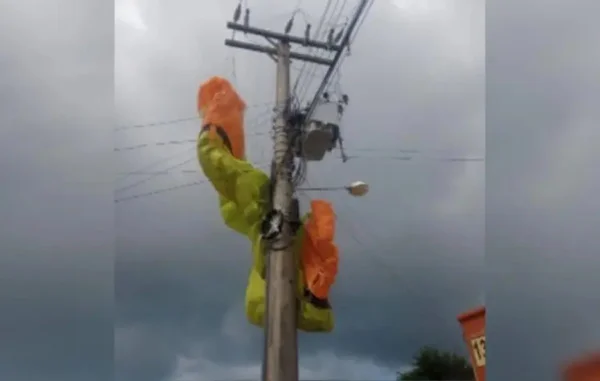 parapente nas cores amarela e laranja fica preso em cima de um poste