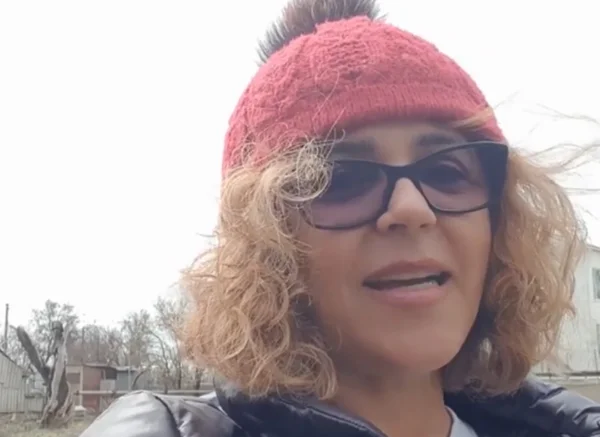 mulher branca e loira usa um gorro vermelho na cabeça enquanto grava um vídeo