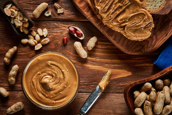 Foto colorida de pasta de amendoim em mesa de madeira - Metrópoles
