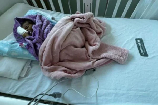 Foto colorida de bebê de poucos meses em leito hospitalar - Metrópoles
