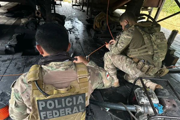 Dois homens uniformizados com a logo da Polícia Federal