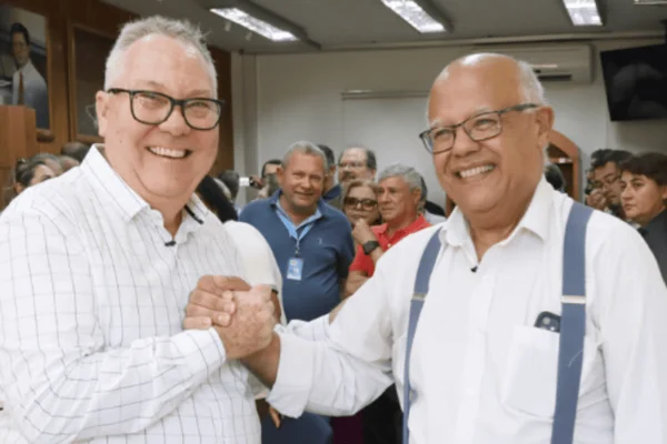 Imagem colorida de dois homens vestidos de branco e apertando as mãos - Metrópoles
