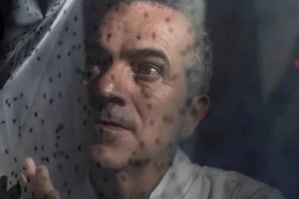 Foto colorida de homem mais velho atrás de um véu que protege contra mosquitos - Metrópoles.