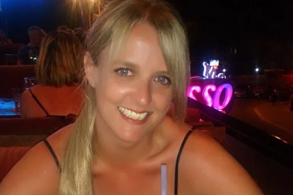 Foto colorida de mulher de cabelos loiros, sorrindo para foto - Metrópoles