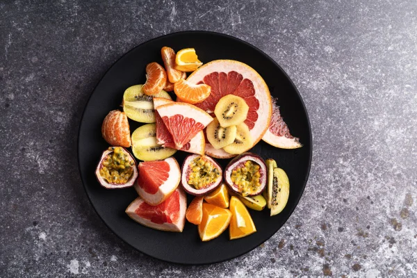 frutas em tons de laranja, amarelo e vermelho em um fundo escuro