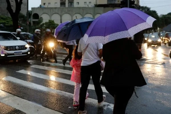 Imagem colorida de pessoas na rua durante chuva