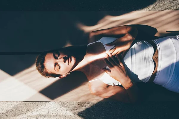 Foto colorida de mulher deitada com os olhos fechados e meditando - Metrópoles