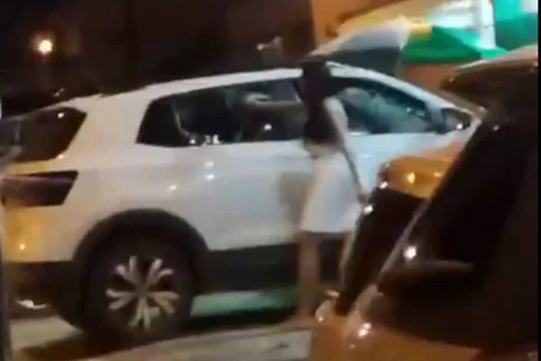 Mulher usando pedra para quebrar vidro do carro do veículo
