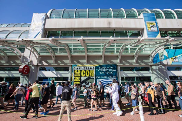 A foto colorida mostra a entrada da San Diego Comic-Con, com pessoas andando pela rua - Metrópoles
