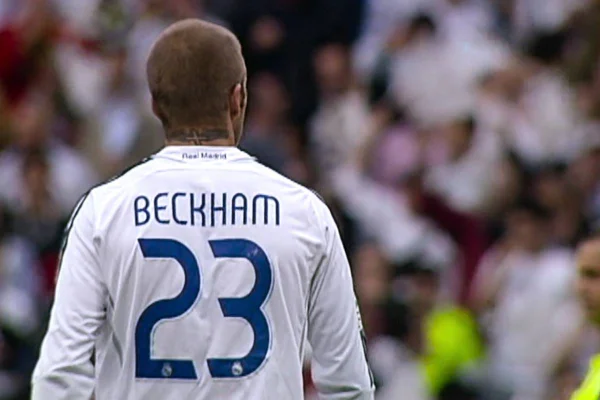 foto colorida do jogador david beckham de costas com blusa de futebol branca com sobrenome dele e o numero 23 - metrópoles