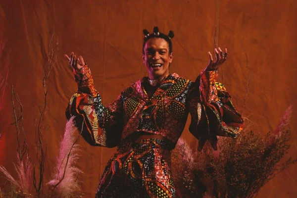 homem negro com roupa colorida posa sorrindo