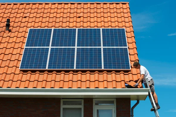 Imagem mostra pessoa colocando placas de energia solar no telhado de uma casa - Metrópoles