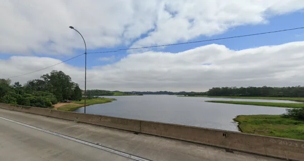 Imagem colorida de braço da Represa Guarapiranga, em Itapecerica da Serra, com trecho de viaduto do Rodoanel