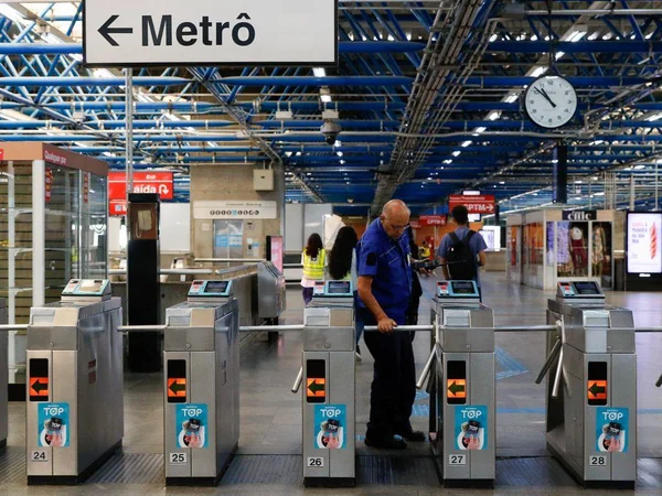 foto colorida: Funcionário do metrô (com camisa azul) verifica catraca da estação Palmeiras-Barra Funda do metrô, em São Paulo