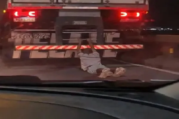 Imagem colorida de homem sendo carregado na traseira do caminhão - Metrópoles