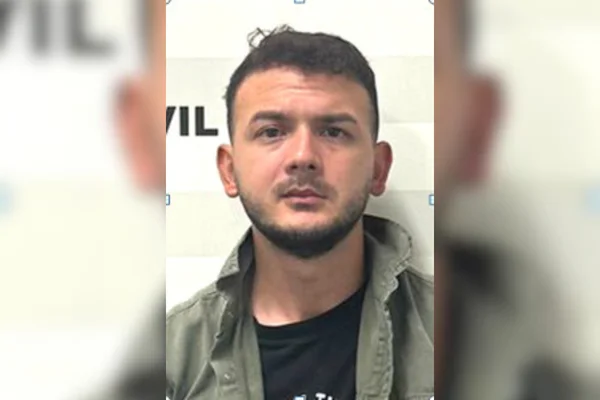Imagem colorida de um homem branco com barba e cabelos pretos, vestido com um casaco verde e camiseta preta - Metrópoles