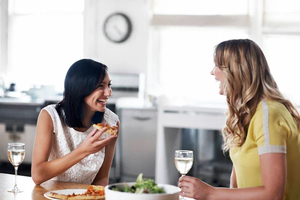 Imagem colorida: duas mulheres comendo e conversando - Metrópoles