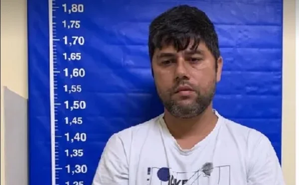 Torcedor do Flamengo com camiseta branca em sala da polícia do Rio com marcações de altura