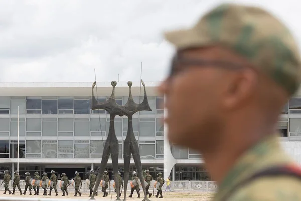 Imagem colorida mostra militar de perfil. Ao fundo, Praça dos Três Poderes / Metrópoles