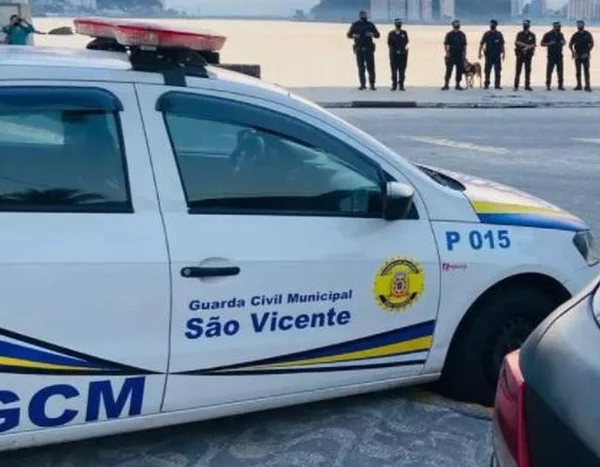 Imagem colorida de viatura da GCM de São Vicente, um carro branco com adesivo e giroflex.